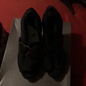Black shoe with mesh and patent leather strap.